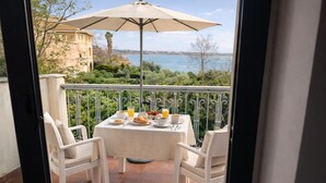 A balcony with a table set for breakfast, overlooking a scenic view of the sea and greenery. - Geranium | 2 bedroom, 2 bath, penthouse near the sea (Anastasi III)