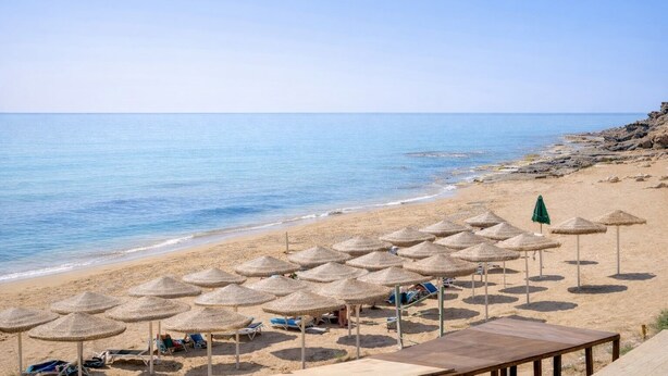 A beach with thatched umbrellas, lounge chairs, and a wooden deck. - Geranium | 2 bedroom, 2 bath, penthouse near the sea (Anastasi III)