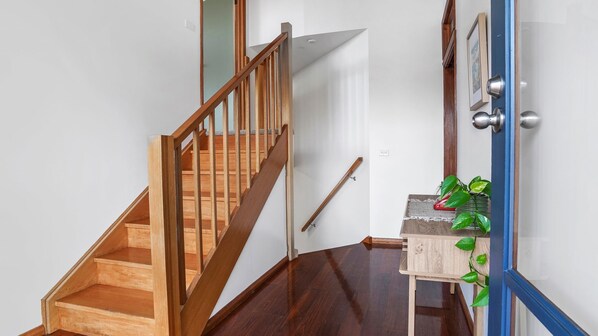 A wooden staircase leading to a landing with a small table and a potted plant.