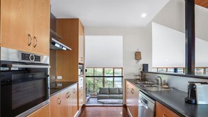 Una cocina moderna con armarios de madera, un horno Bosch, un ventanal y vistas al verdor.