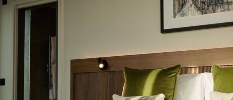 A hotel room with a bed, a headboard with a light fixture, and a framed picture on the wall.