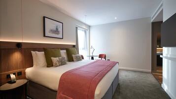 A modern hotel room with a large bed, bedside tables, a desk, and a chair.