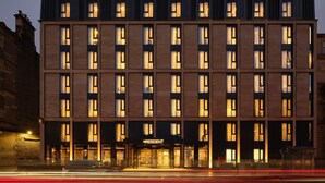 A modern hotel with a symmetrical facade, multiple windows, and a prominent entrance.