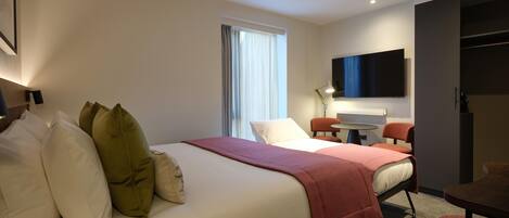 Una habitación de hotel moderna con una cama grande, un escritorio y un televisor.