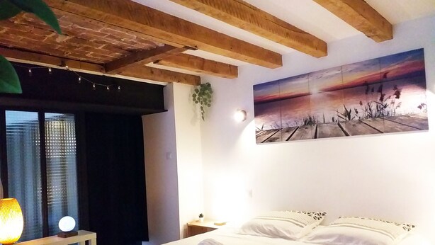 A hotel room with a bed, a nightstand, a lamp, and a painting on the wall.