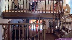 A spacious loft with a wooden staircase, a balcony with a view, and a cozy seating area.