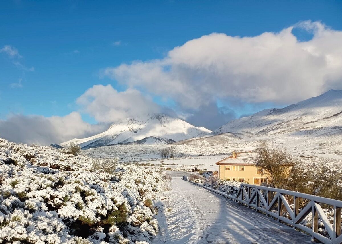 Un paysage enneigé avec une maison et un pont.