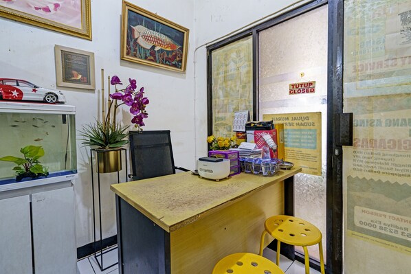 A reception desk with a computer, a potted plant, and a small aquarium.
