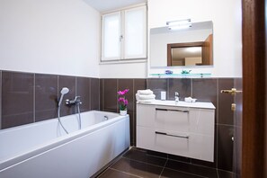 Un bagno moderno con una vasca, un mobile lavabo con specchio e un'orchidea in vaso.