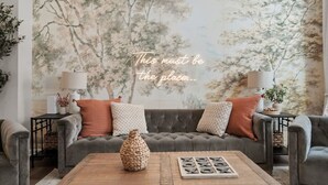 A cozy living room with a grey sofa, patterned cushions, a woven vase, and a tic-tac-toe game on a wooden coffee table. - High-End 4bd: hottub, Mini golf, gameroom, firepit (Pittsburgh)