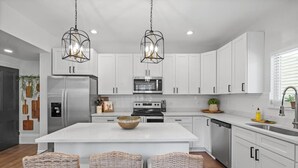 A modern kitchen with white cabinets, stainless steel appliances, and a central island with a bowl. - High-End 4bd: hottub, Mini golf, gameroom, firepit (Pittsburgh)