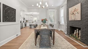 A modern kitchen with white cabinets, a central island, and a dining area with a wooden table and chairs. - High-End 4bd: hottub, Mini golf, gameroom, firepit (Pittsburgh)