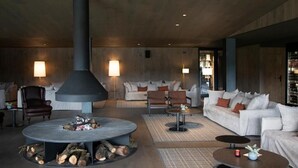 Een moderne lounge met een ronde tafel in het midden, banken en een grote pilaar.