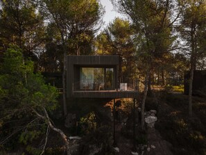 A modern cabin with a wooden deck, surrounded by trees and rocks. - Les Cabanes de l Oller (Manresa)