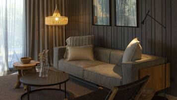 En moderne stue med en sofa, et rundt sofabord, et sengebord og en hængende lampe.