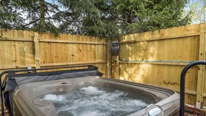 A hot tub with a wooden fence and trees in the background.