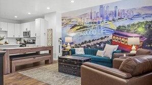 A modern living room with a cityscape mural, a sofa, a coffee table, and a dining area with a bench.