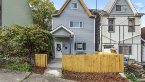A two-story house with a gabled roof, a front porch, and a wooden fence.