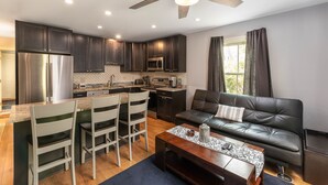 A modern kitchen with dark cabinets, stainless steel appliances, and a dining area with white chairs. - Perfect Location in North Conway Village

 (Conway)