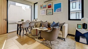 A modern living room with a sofa, chairs, a coffee table, and a bookshelf. - OYO Life 92719 Rolling Hills Residence Karawang (Karawang)