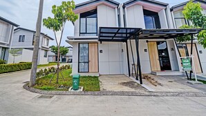 A modern residential building with a gated entrance, numbered doors, and a green rental sign. - OYO Life 92719 Rolling Hills Residence Karawang (Karawang)