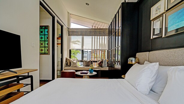 A hotel room with a large bed, a sofa, a small table, and a TV. - OYO Life 92719 Rolling Hills Residence Karawang (Karawang)