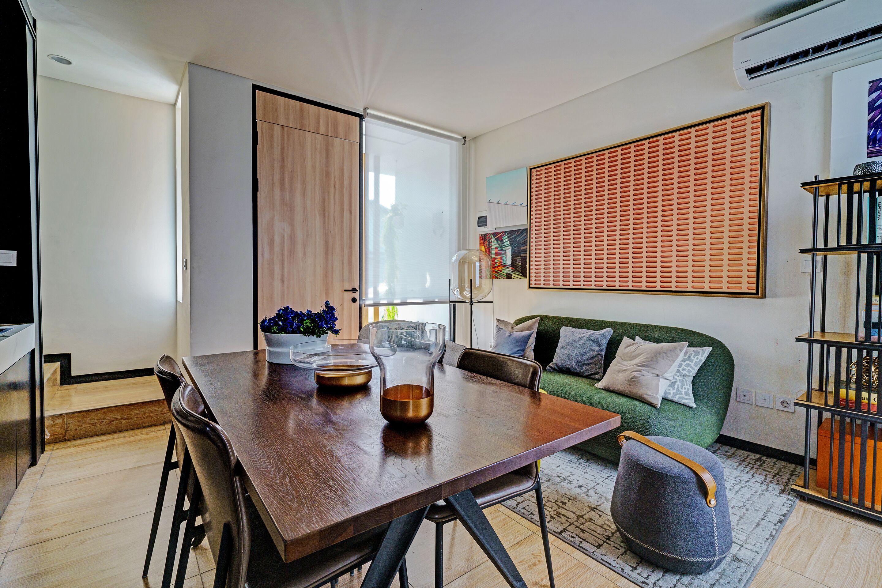 Una sala de estar moderna con una mesa de comedor de madera, un sofá verde y una mesa de centro de vidrio.