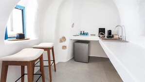 Moderni keittiö, jossa on valkoiset seinät, pieni pesuallas ja baarituolit.