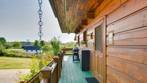 A wooden deck with a green floor, a barbecue grill, and a trash can. - Warm & Cozy Clayton Cabin Near St Lawrence River! (Clayton)