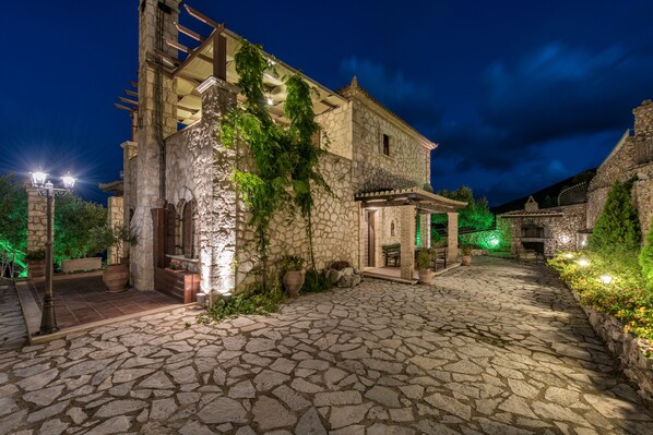 Un edificio de piedra con fachada rústica, un patio empedrado y zonas de estar al aire libre.