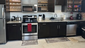A modern kitchen with dark cabinetry, stainless steel appliances, and a granite countertop.