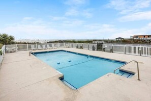Una piscina rectangular con un deck blanco y una cerca blanca que la rodea.