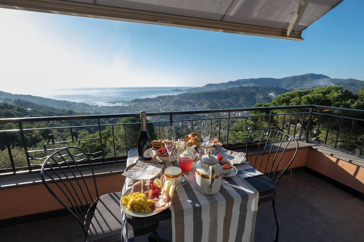 Un balcon avec une table préparée pour le petit-déjeuner, offrant une vue sur un paysage magnifique.