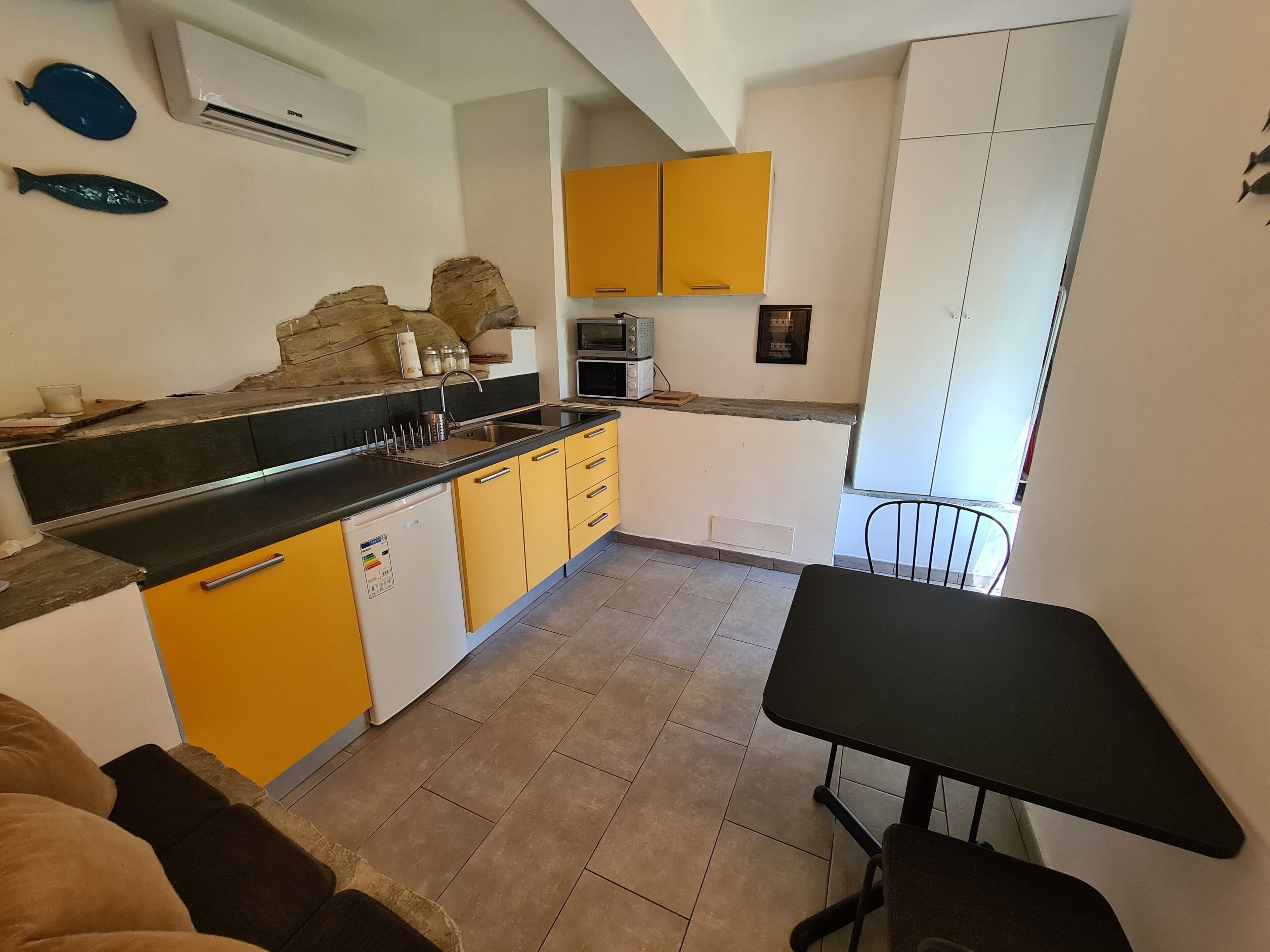 A compact kitchen with yellow cabinets, a black countertop, and a small dining table.