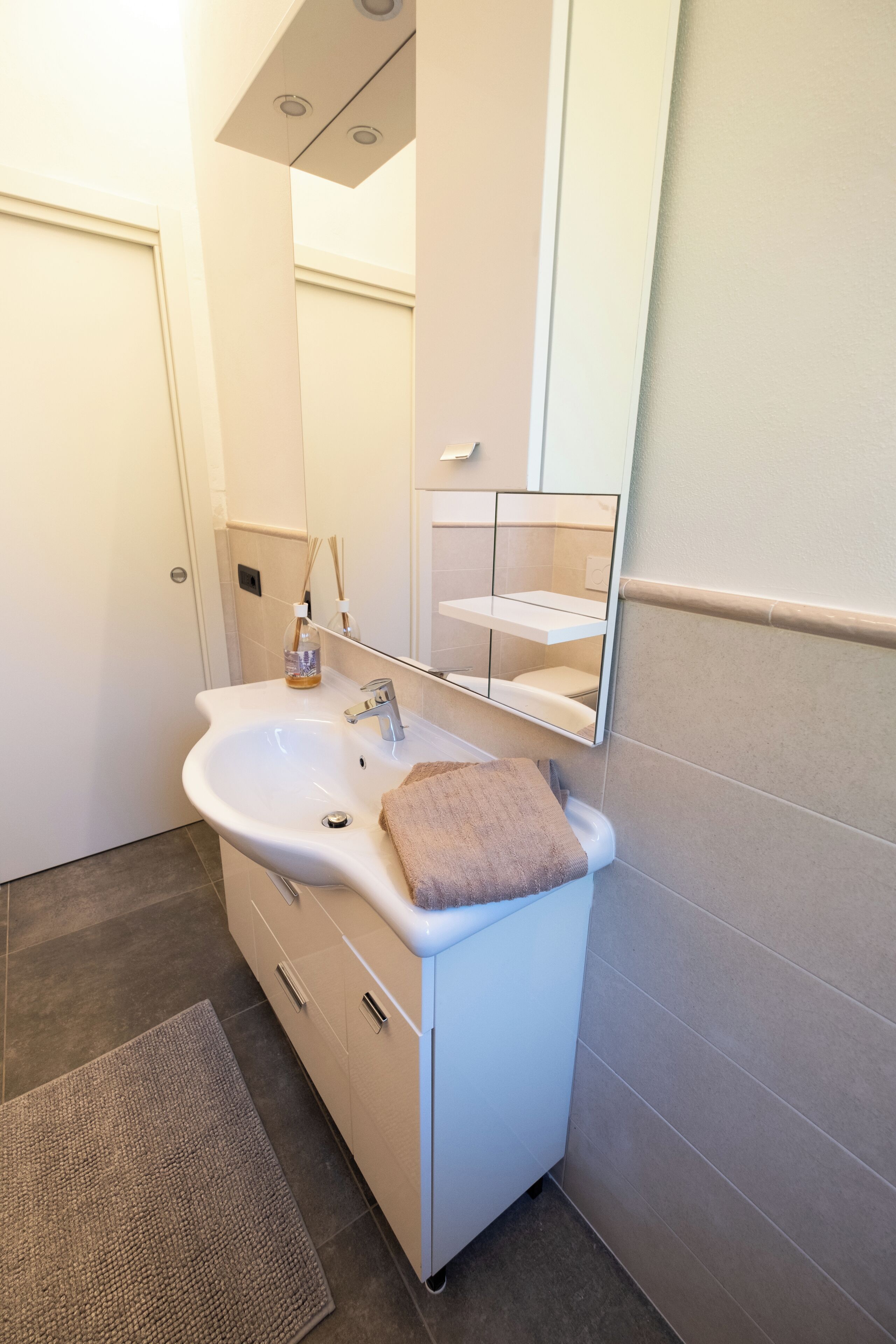 Une salle de bain avec un lavabo blanc, un miroir et une serviette.
