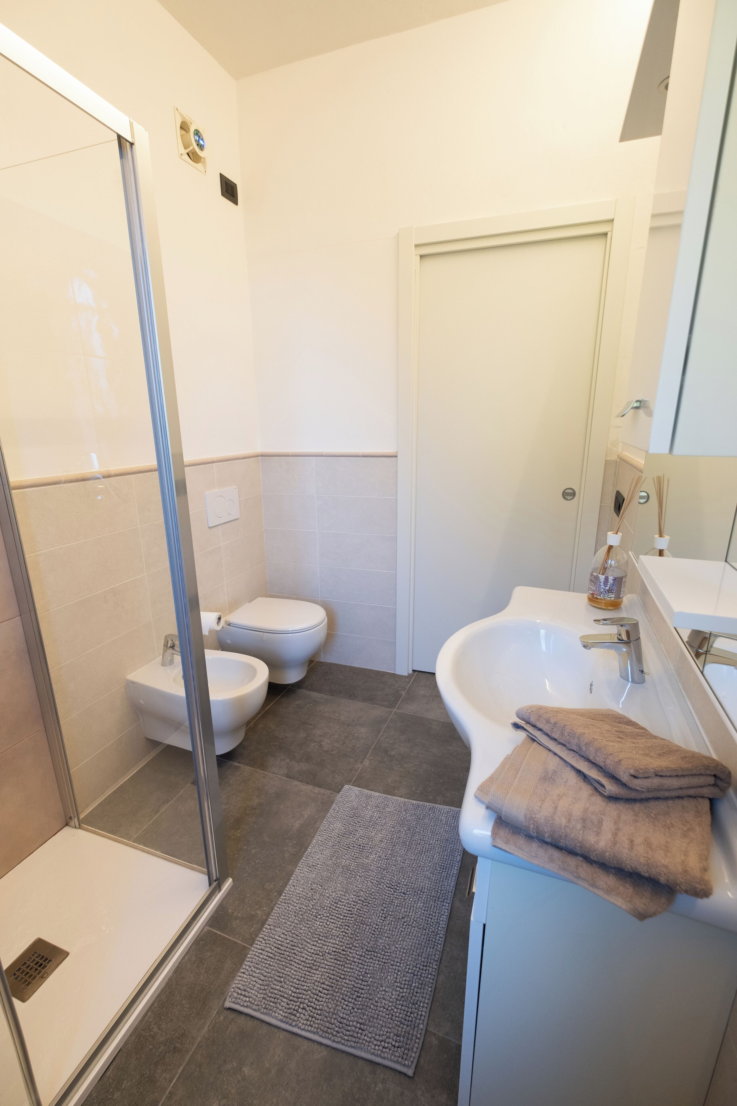 A modern bathroom with a glass shower enclosure, a white sink, and a toilet.