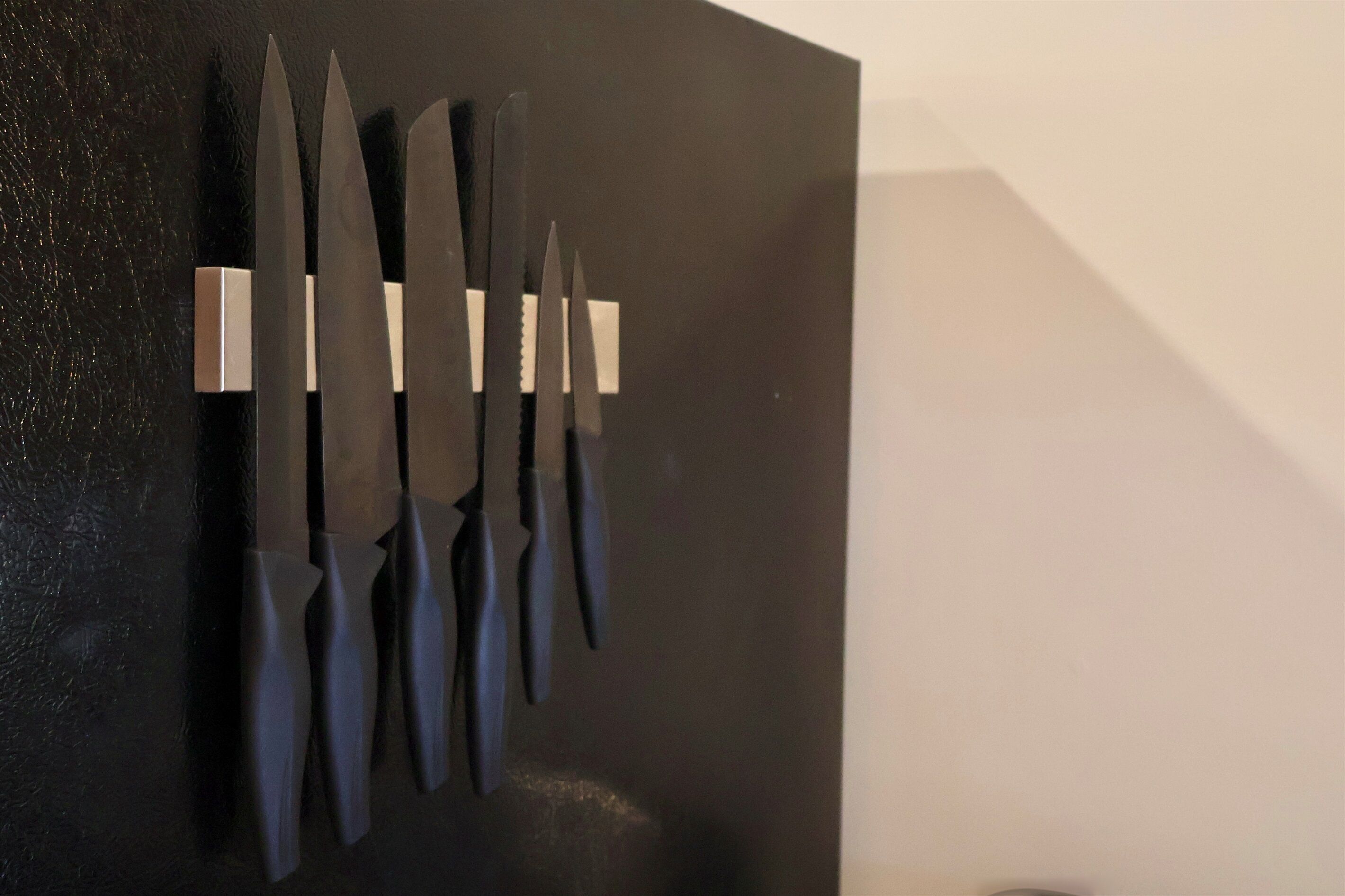 A wall-mounted knife display with six knives.