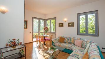 A spacious living room with a large sofa, a glass coffee table, and a dining area with chairs and a table.