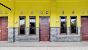 A building with a yellow facade, numbered doors, and a tiled entrance. - OYO Life 92841 Kos 88 (Perean Tengah)