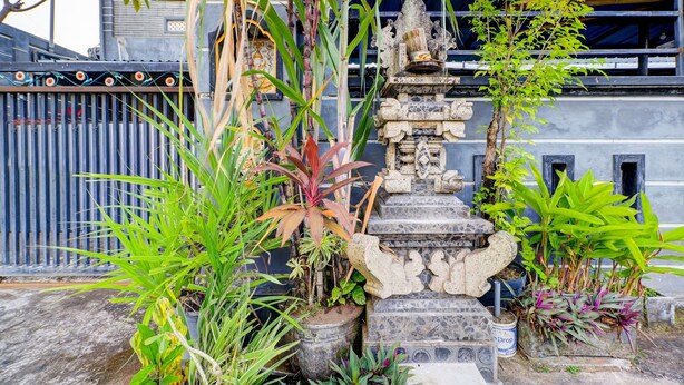 A stone staircase leading to a small shrine, surrounded by various potted plants. - OYO Life 92841 Kos 88 (Perean Tengah)