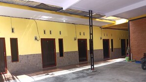 A building with yellow walls, multiple doors, and a concrete floor. - OYO Life 92920 Rumah Kost Azca (Sidoarjo)