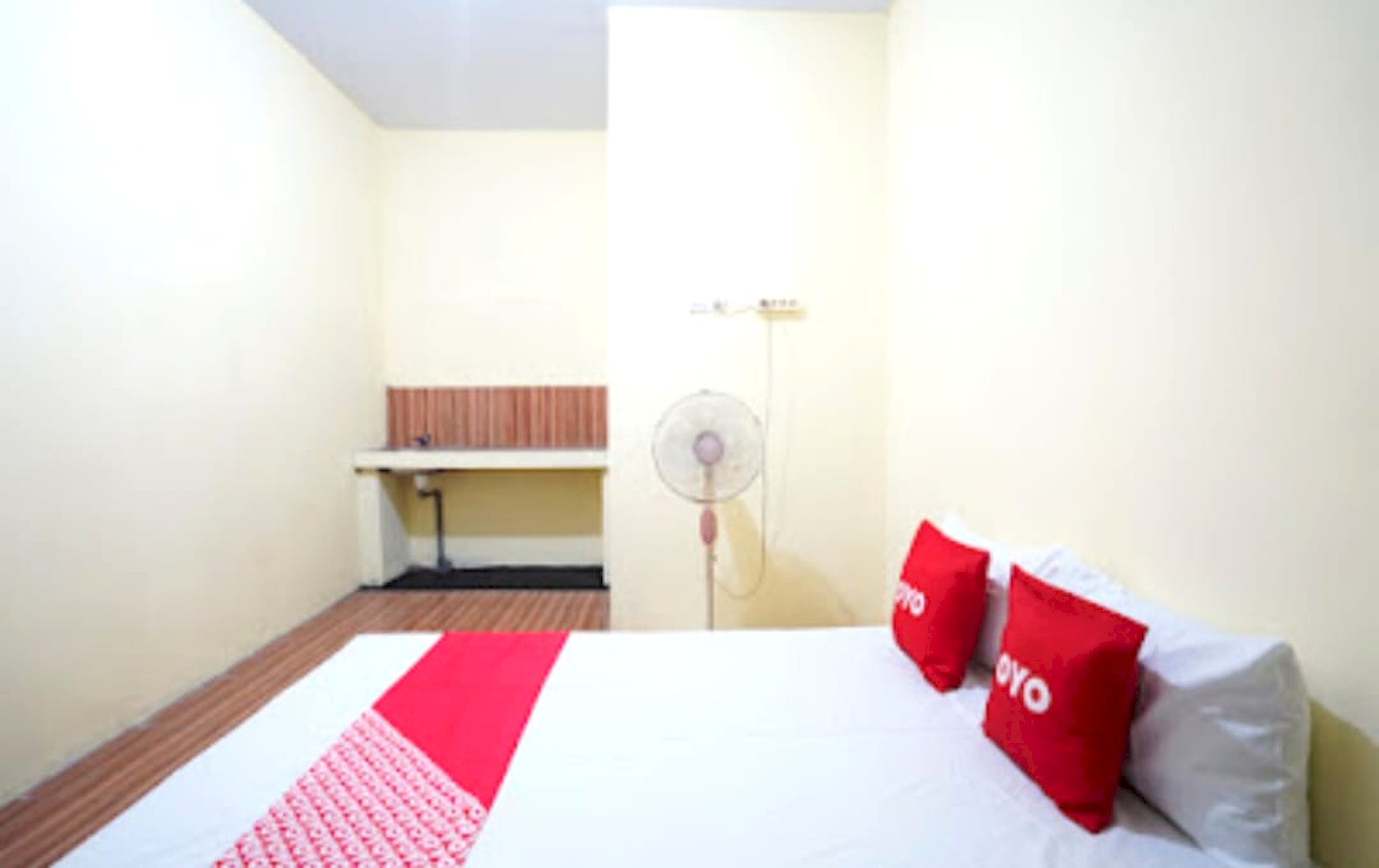 Una habitación de hotel con cama, escritorio y ventilador.