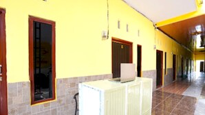A hallway with yellow walls, a tiled floor, and a radiator. - OYO Life 92920 Rumah Kost Azca (Sidoarjo)
