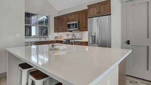 A modern kitchen with wooden cabinets, stainless steel appliances, and a large island.