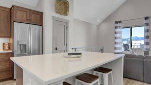 A modern kitchen with a central island, stainless steel appliances, and a view of the outdoors.