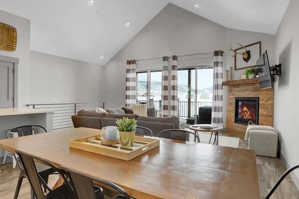 Un salon moderne doté d’une cheminée, d’un coin repas et offrant une vue sur l’extérieur.