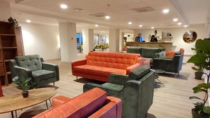 Un hall d'entrée moderne, doté de sièges confortables, d'un comptoir de réception et d'un bar bien visible.