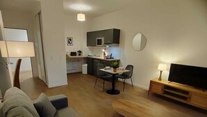 Un salon moderne comprenant un canapé, une table basse, un téléviseur et un coin repas avec des chaises et une table.