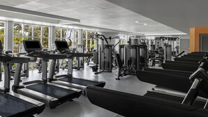 Une salle de sport équipée de tapis de course, d’appareils de musculation et de bancs.