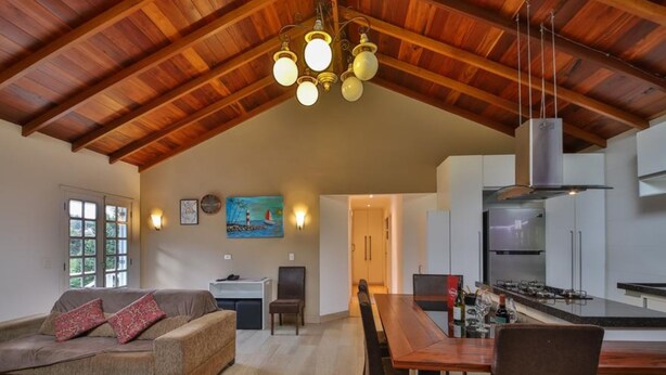 Un amplio salón con techo de madera, una mesa de comedor y una cocina con electrodomésticos modernos.